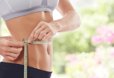 fit girl measuring waist with tape